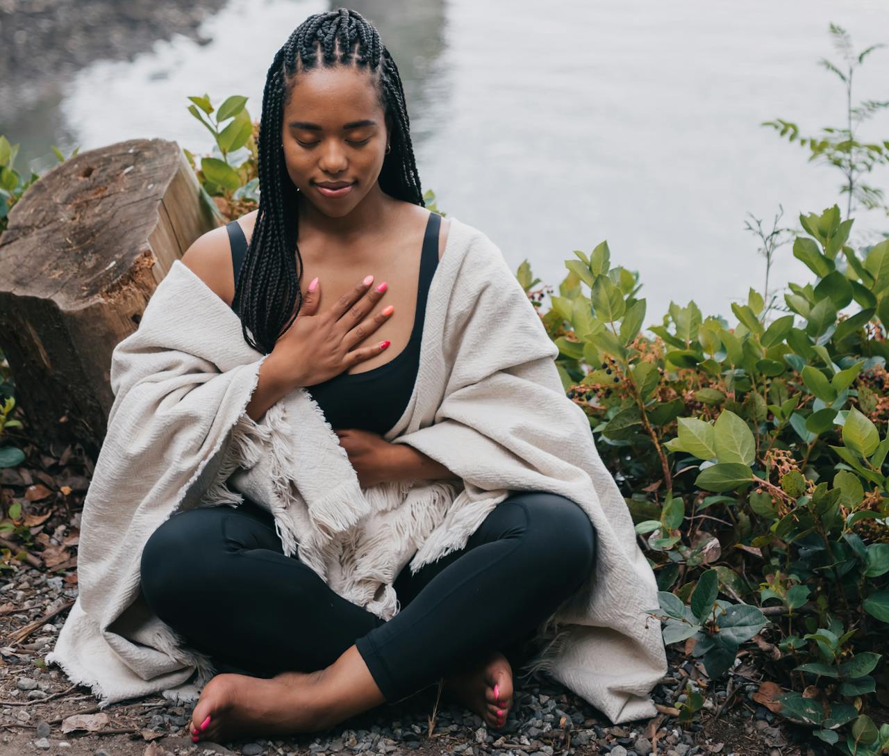 services-05 A woman practicing mindful meditation outdoors by the water, symbolizing wellness and relaxation.